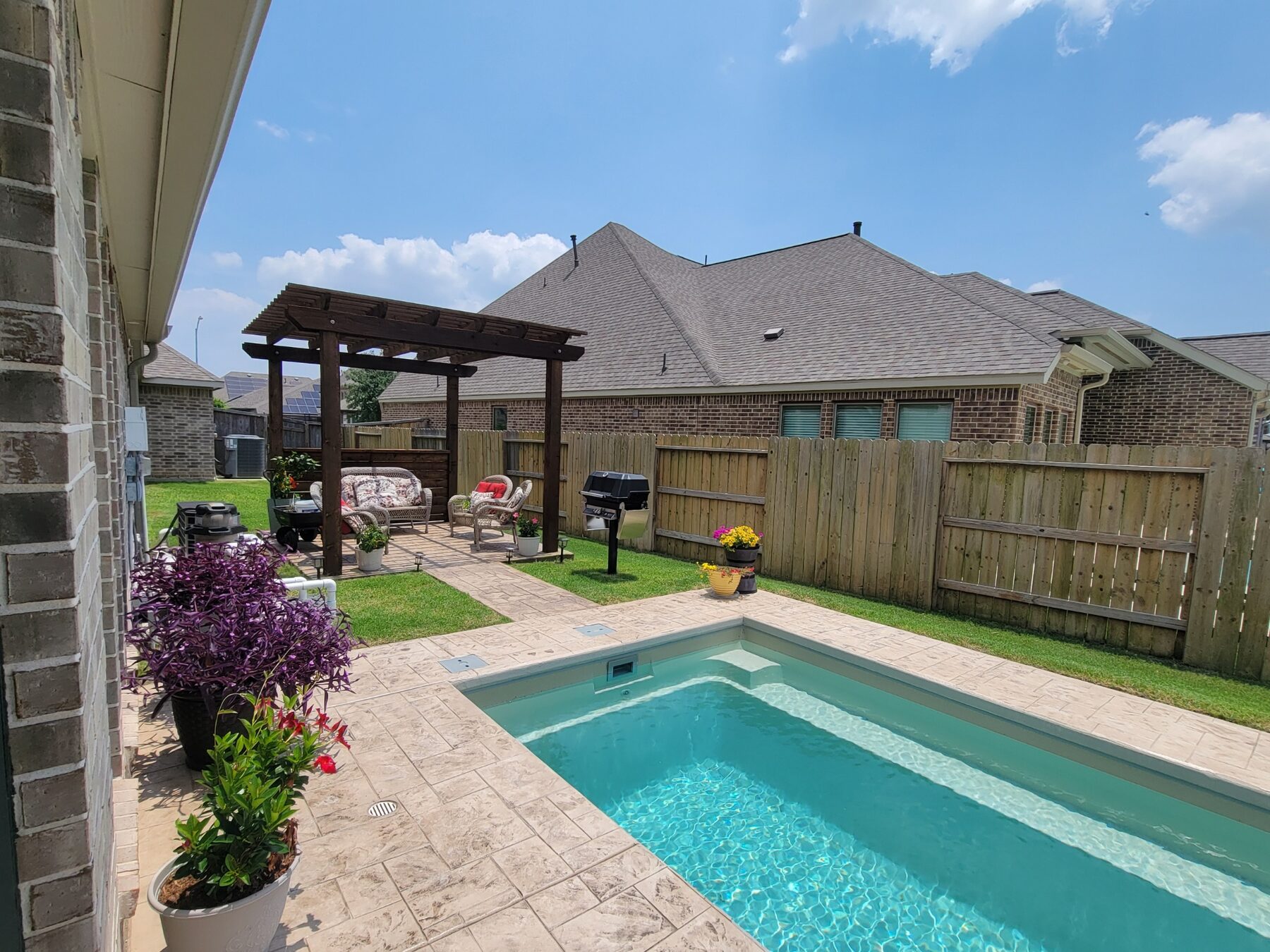 Backyard pool with pergola and stamped deck