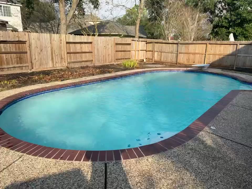 Finished kidney-shaped pool with brick coping after replaster